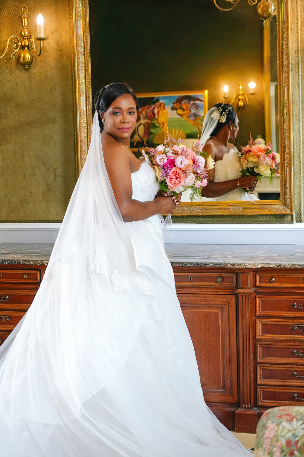Mariée et son bouquet devant un miroir doré